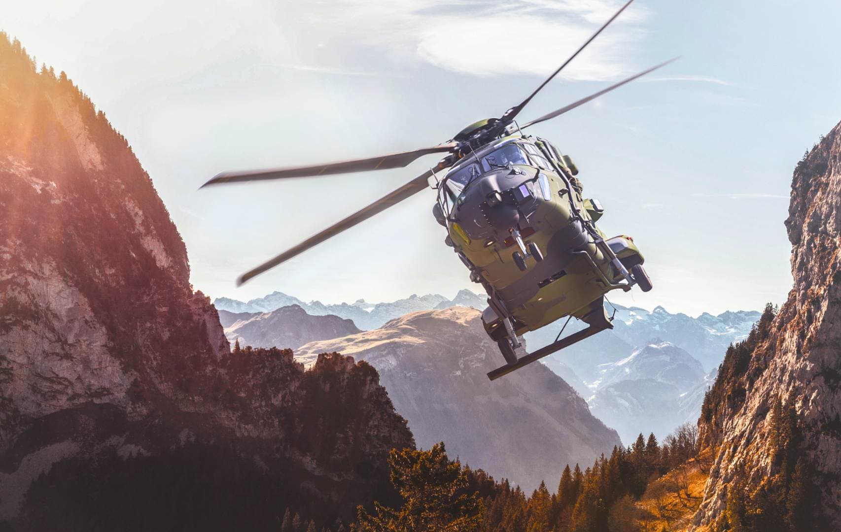 Military helicopter flying through a mountain pass